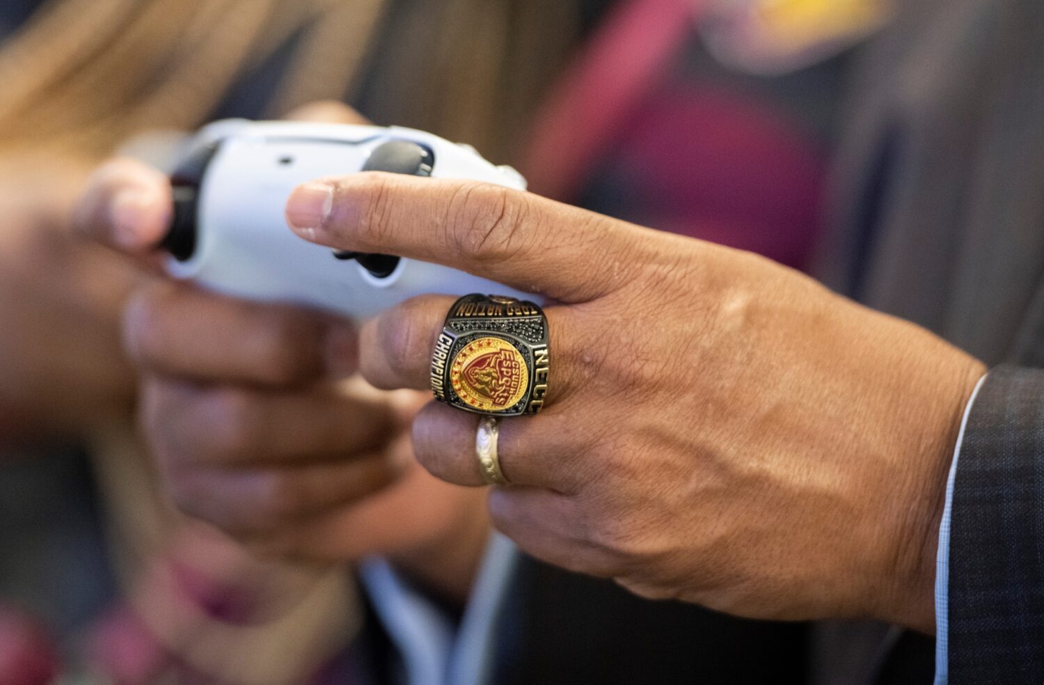 Someone holding a game controller, wearing an Esports championship ring.