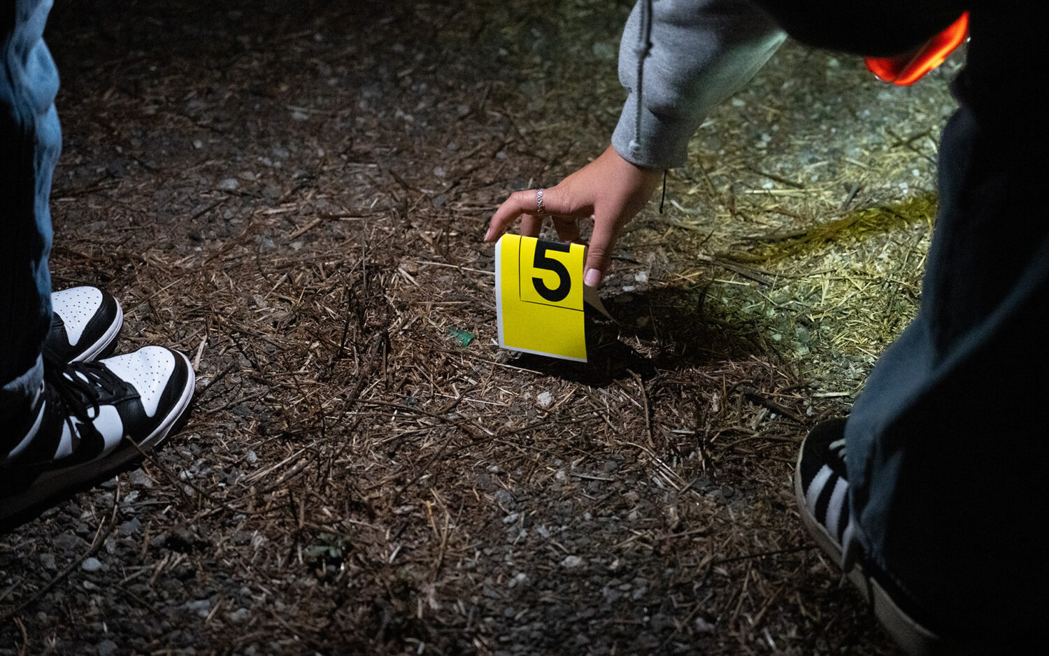 Someone places a crime scene marker on the ground.