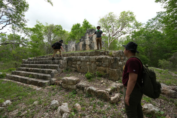 Students ascend steps of Maya structure.