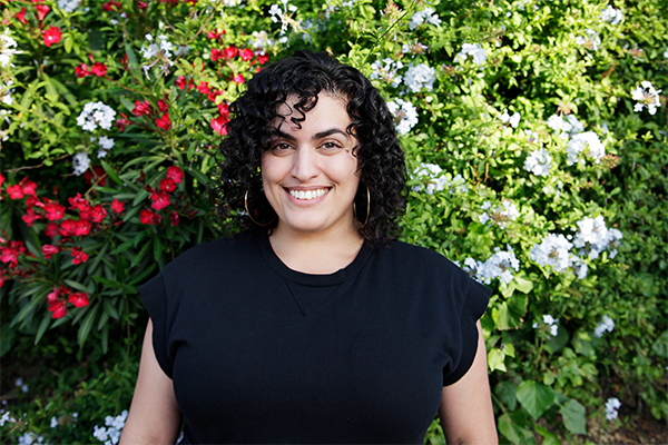 Tahereh Aghdasifar in black shirt with flowers in background.