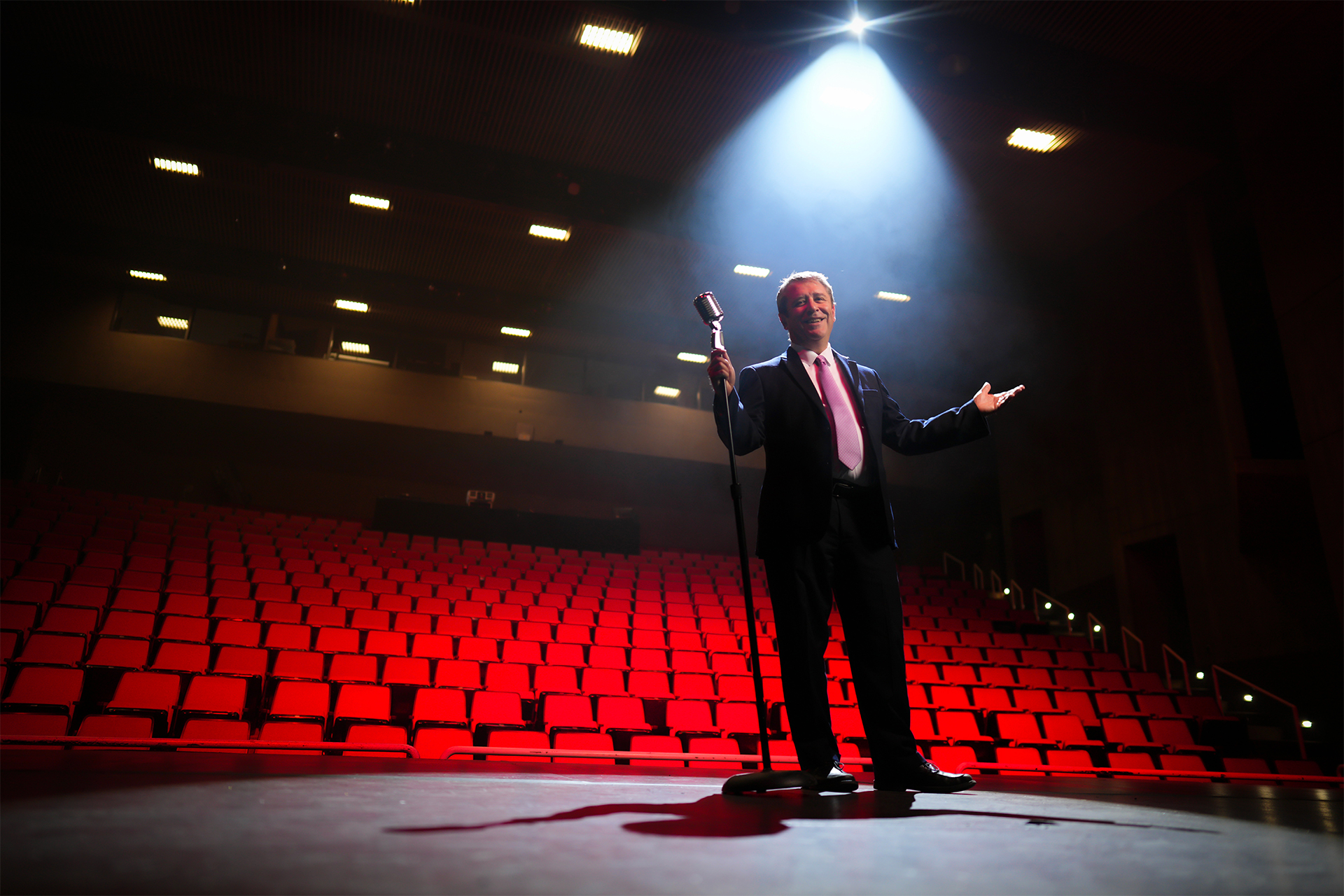 Dean Caron on stage lit by spotlight