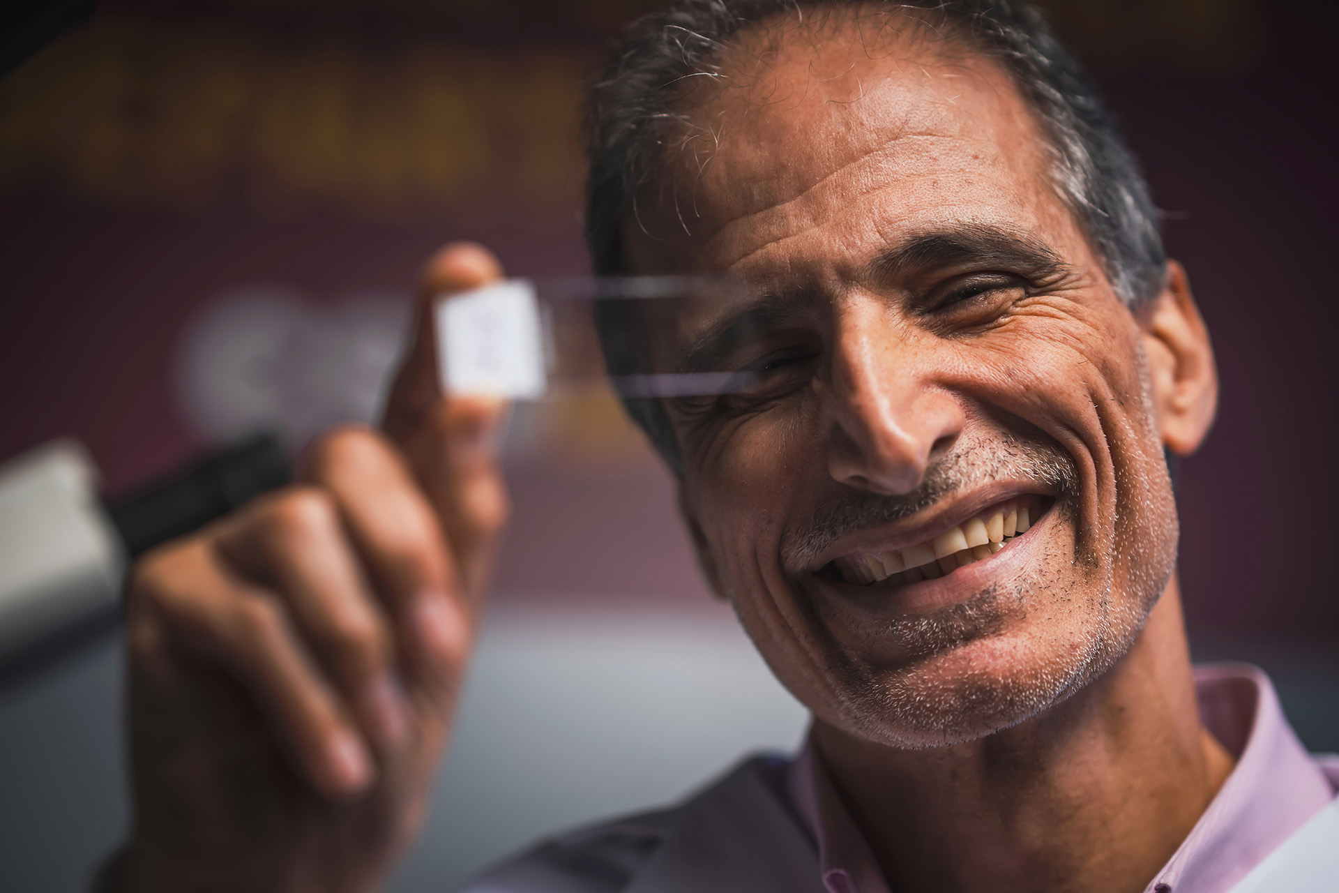 Jahan Abdi holds up a microscope slide.