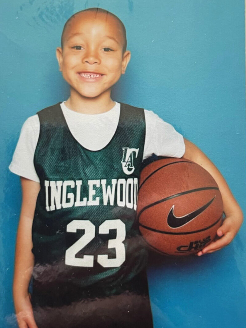 Jeremy as a grade-schooler in a basketball jersey, holding a ball.
