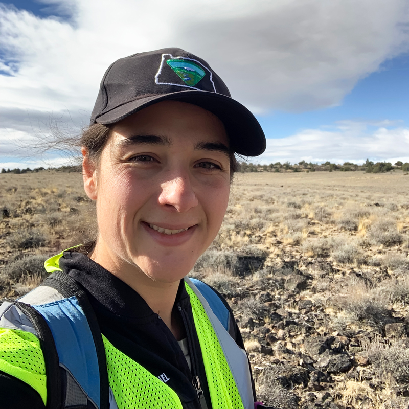 Portrait of Gendron in a high-visibility vest with shrubland in background